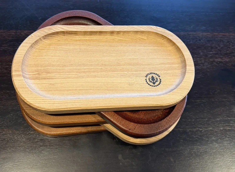 Stoh oválnych drevených tácok v rôznych odtieňoch, vrchná tácka s logom Antlerwood